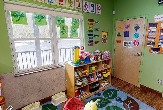 Playroom with a toy shelf, window, and green walls