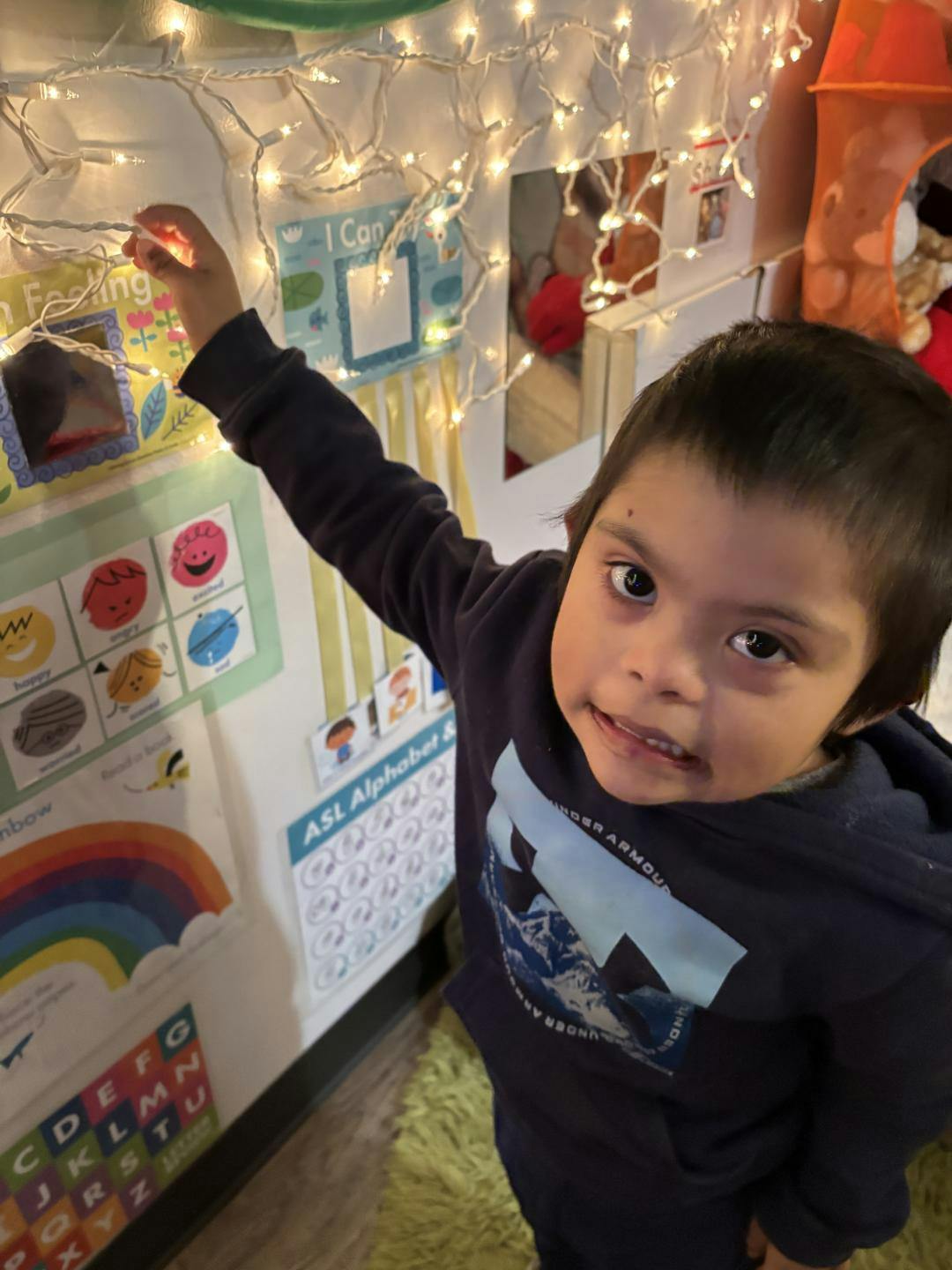 Child looking up, touching string lights with colorful educational charts