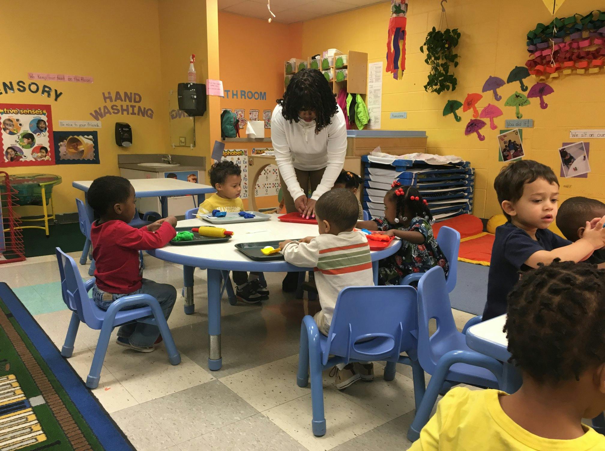 Adult and children at tables in a classroom