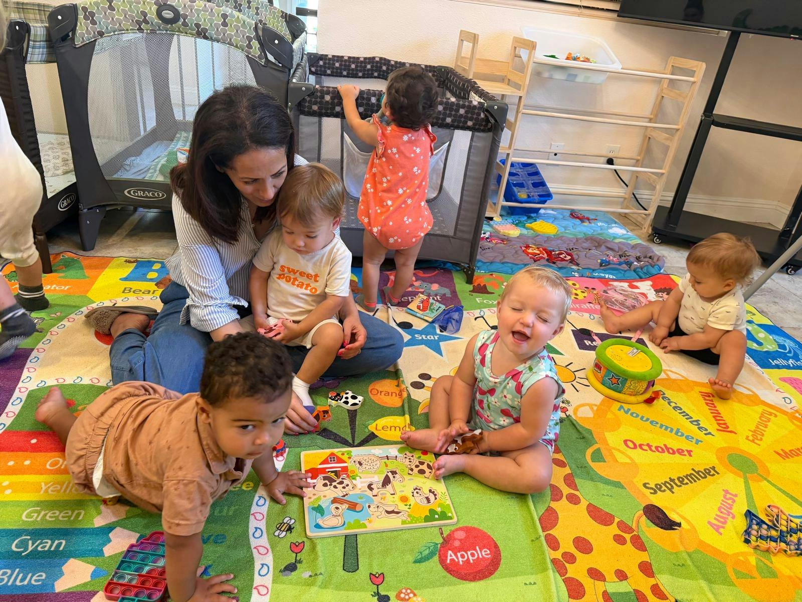 A person sitting on a play mat with several children playing