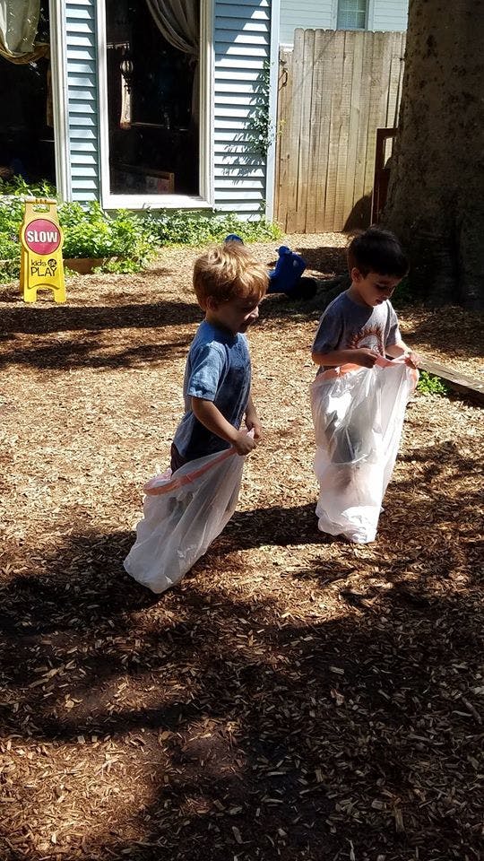 Two children standing in plastic bags on wood chips