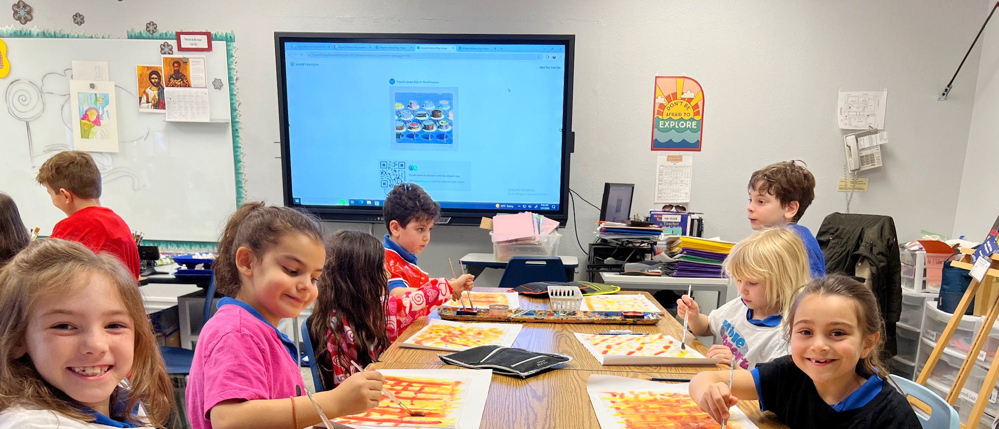 Children painting at tables in a classroom