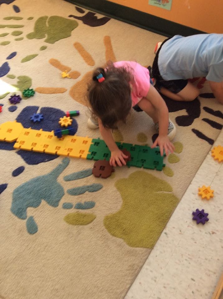 Child playing with colorful interlocking blocks on a patterned rug