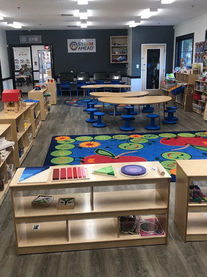 Classroom with tables, chairs, and shelves with learning materials