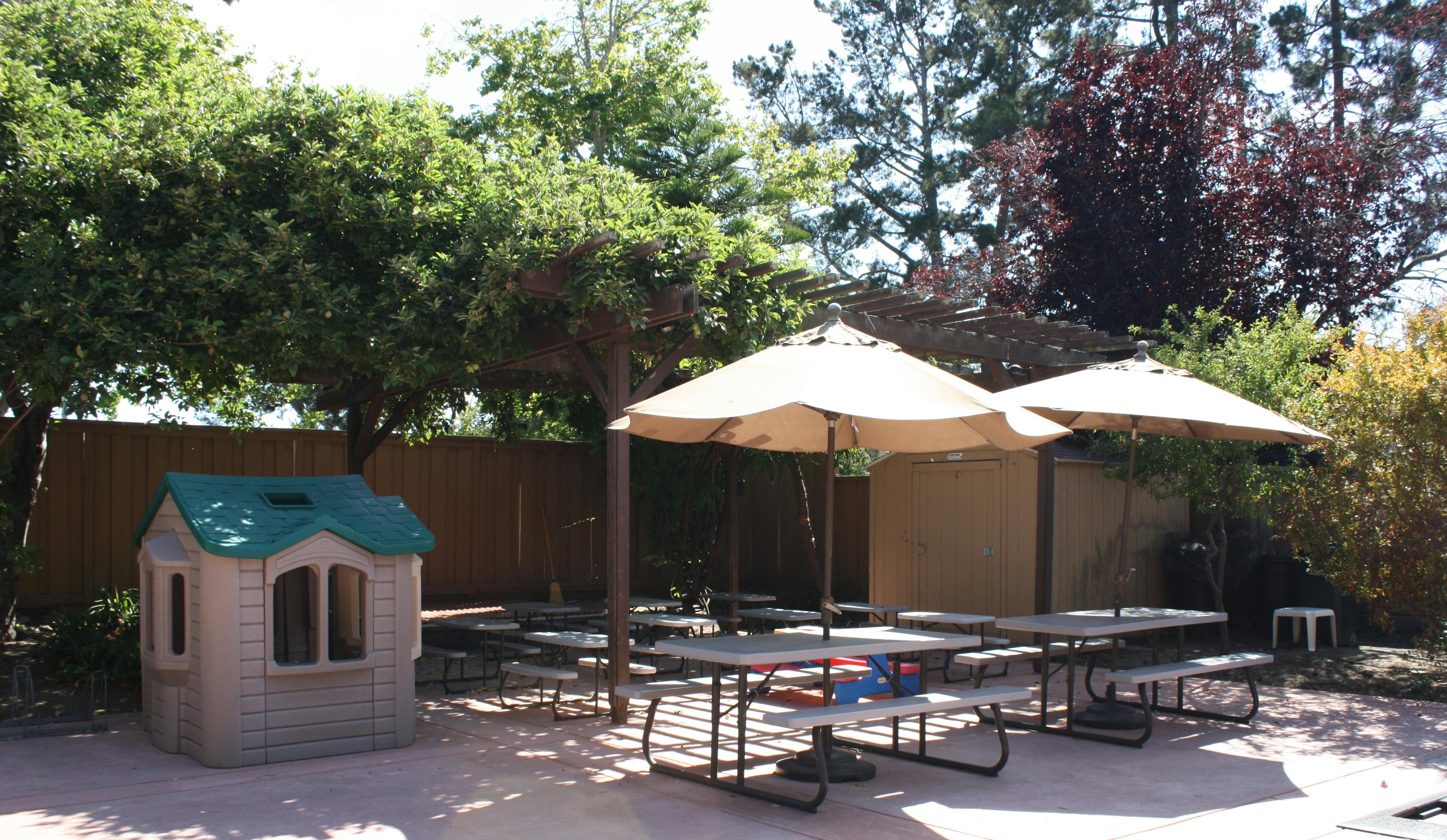 Playhouse and picnic tables with umbrellas