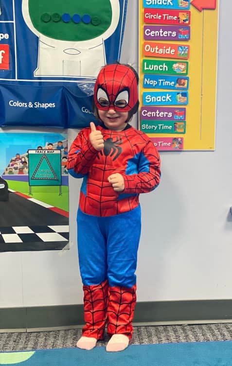 Child in a Spider-Man costume giving a thumbs up