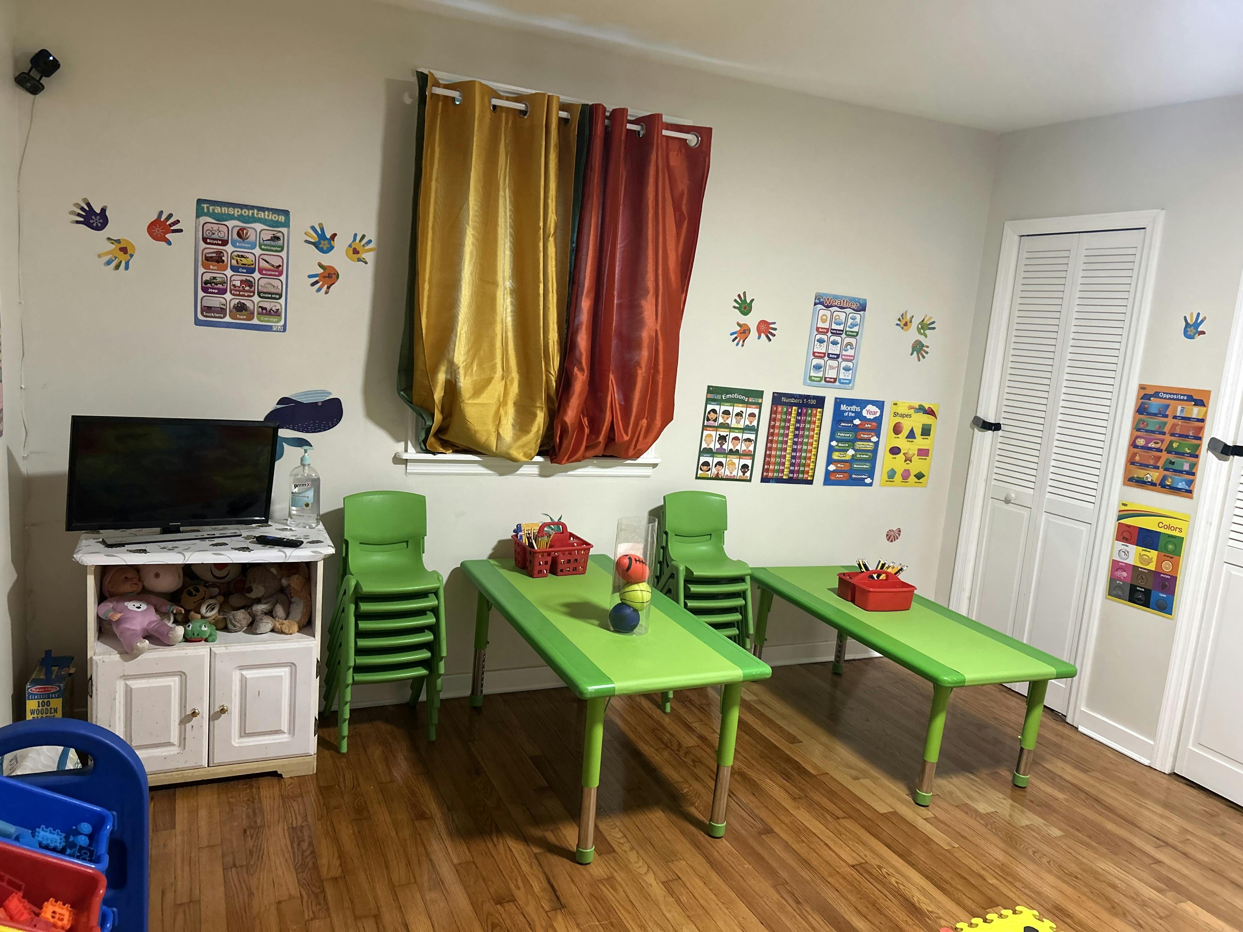 Classroom with green tables and chairs, educational posters on walls