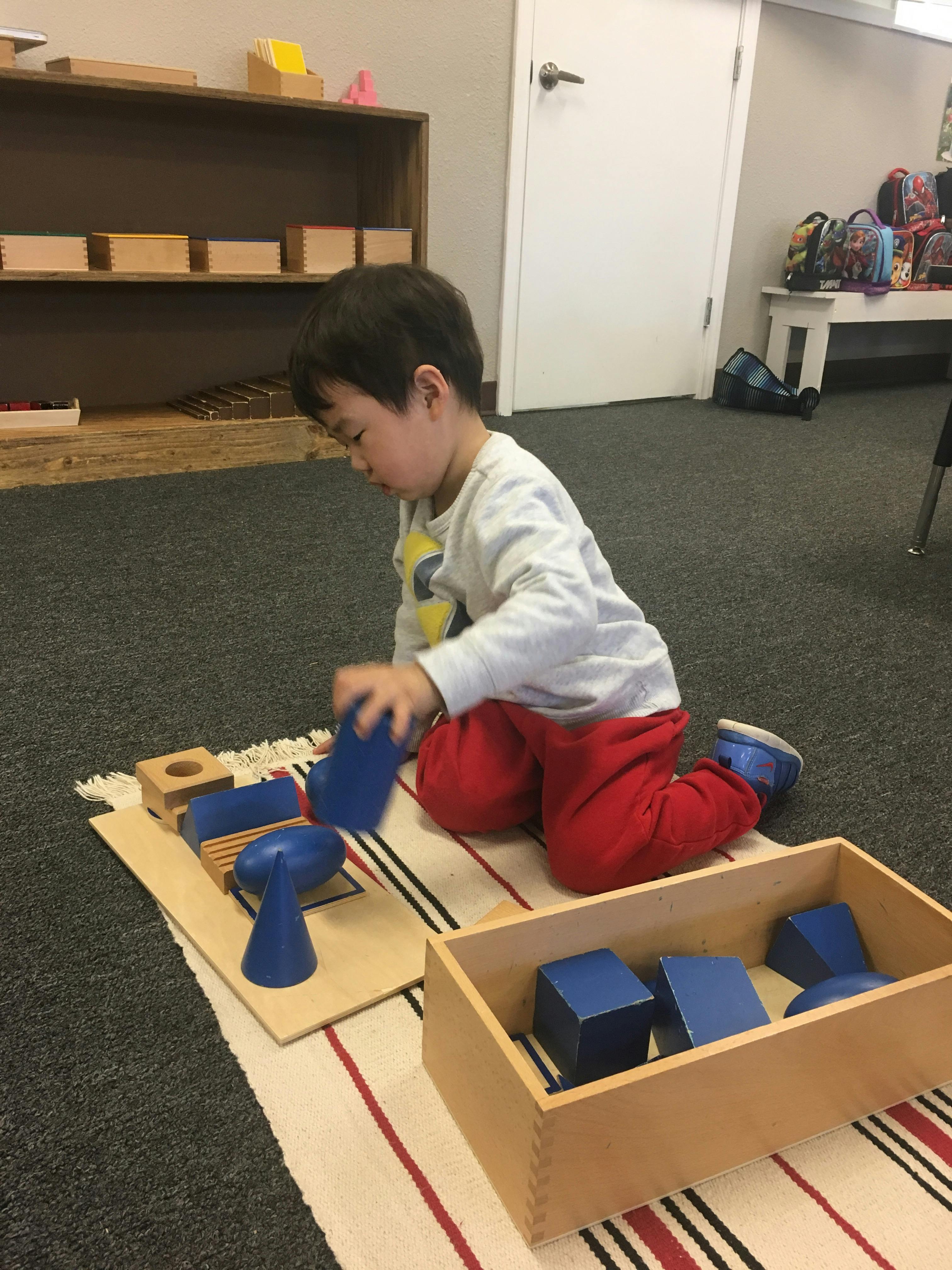 Child playing with blue geometric blocks on a mat