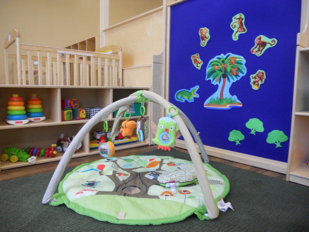 Baby play mat with toys in a room with a crib and shelves