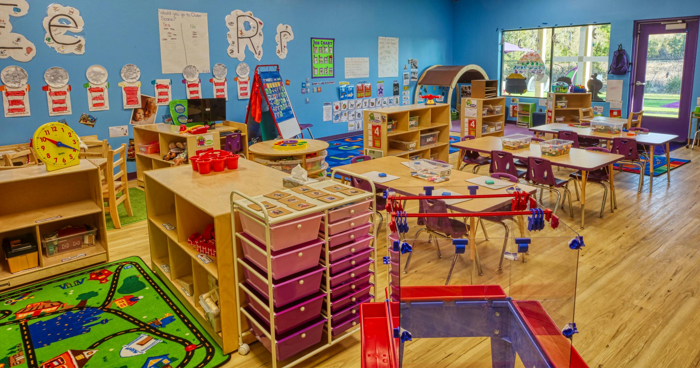 Classroom with tables, chairs, shelves, and colorful learning materials