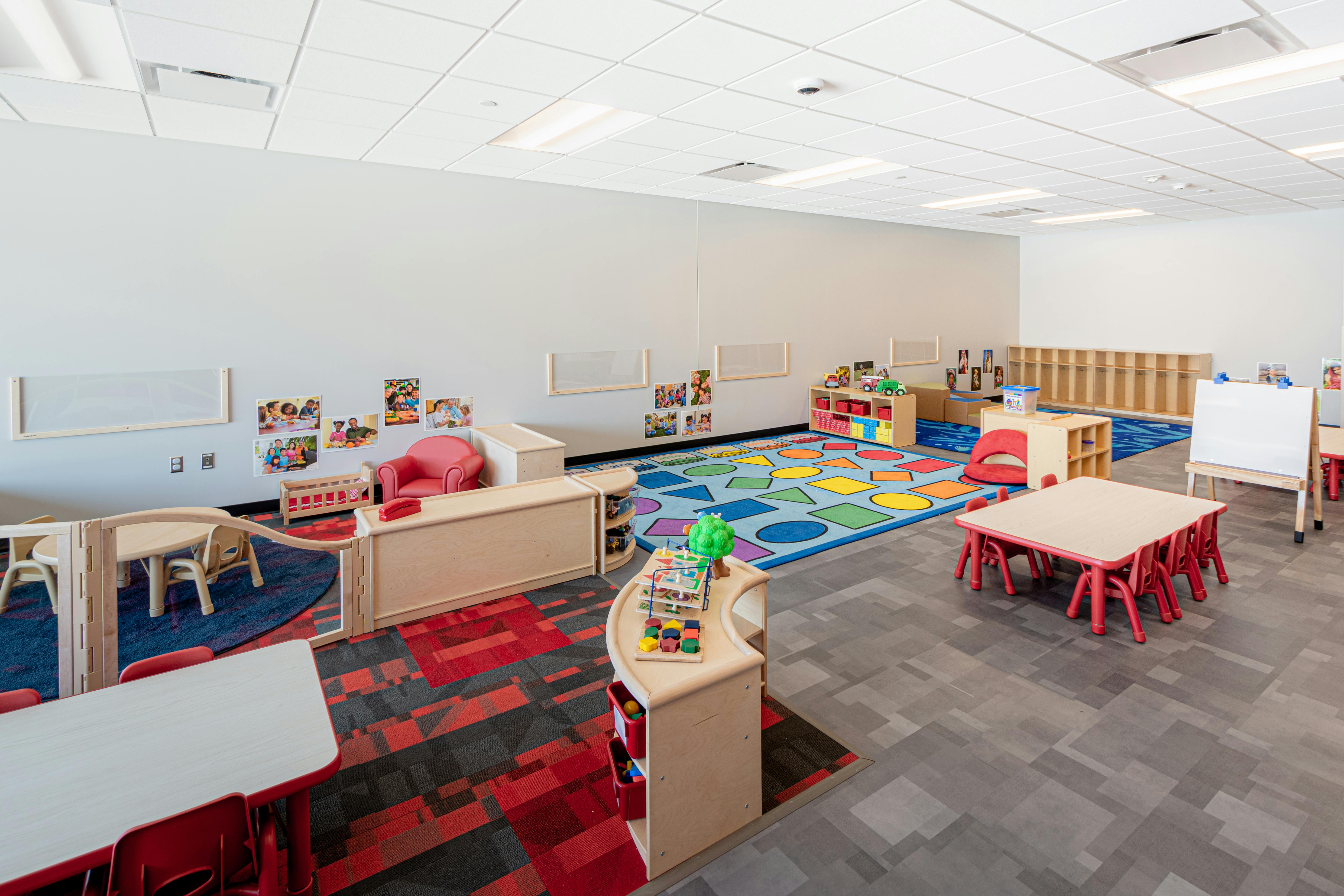 Empty classroom with small tables, chairs, and colorful rugs
