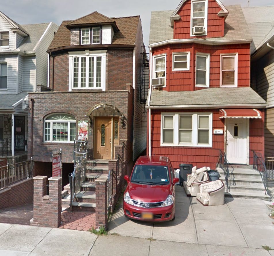 Two houses side by side with a red car parked in front of one