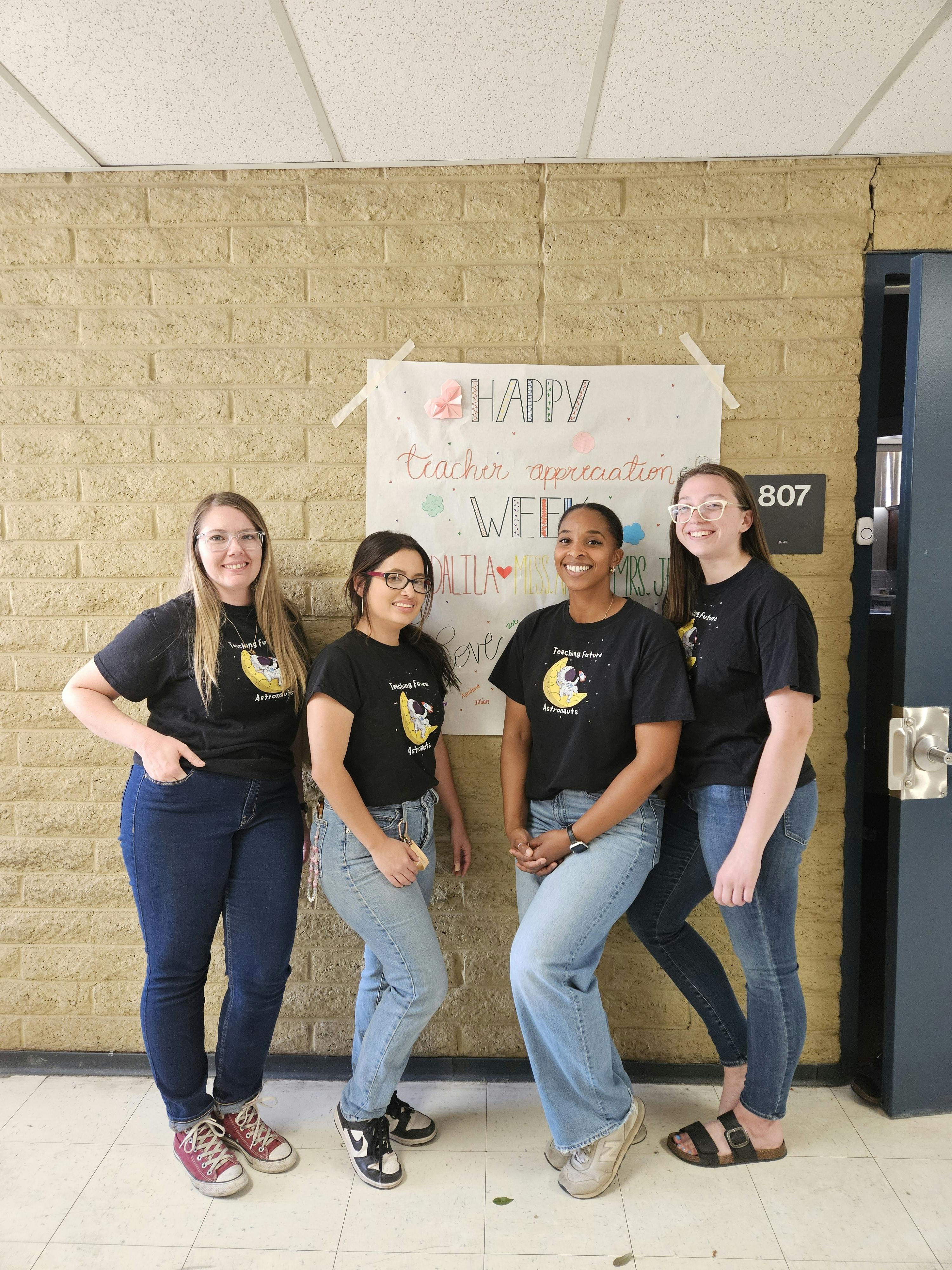 Four people standing in front of a poster that says "Happy Teacher Appreciation Week"