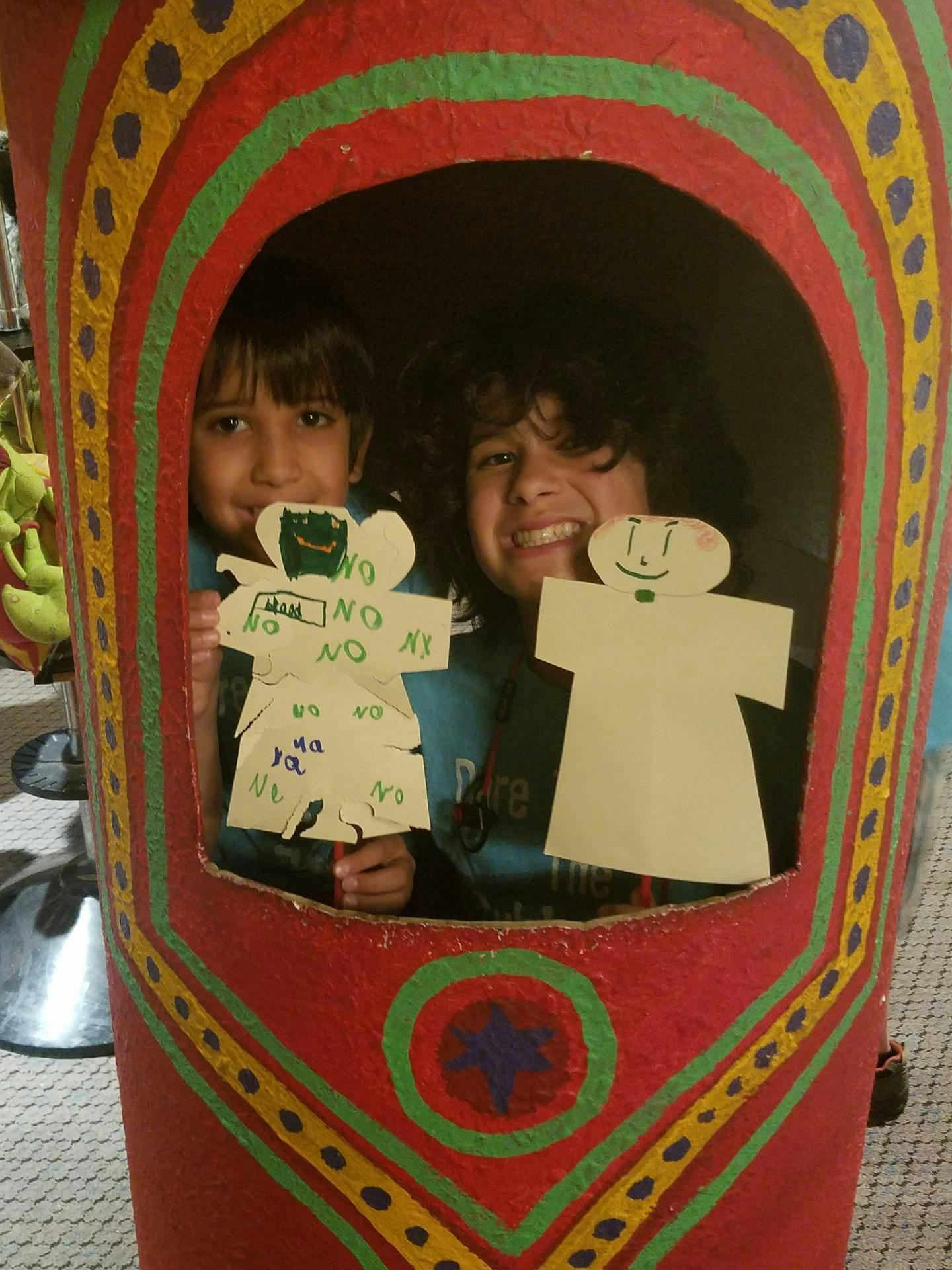 Two children holding paper cutouts in a decorated box