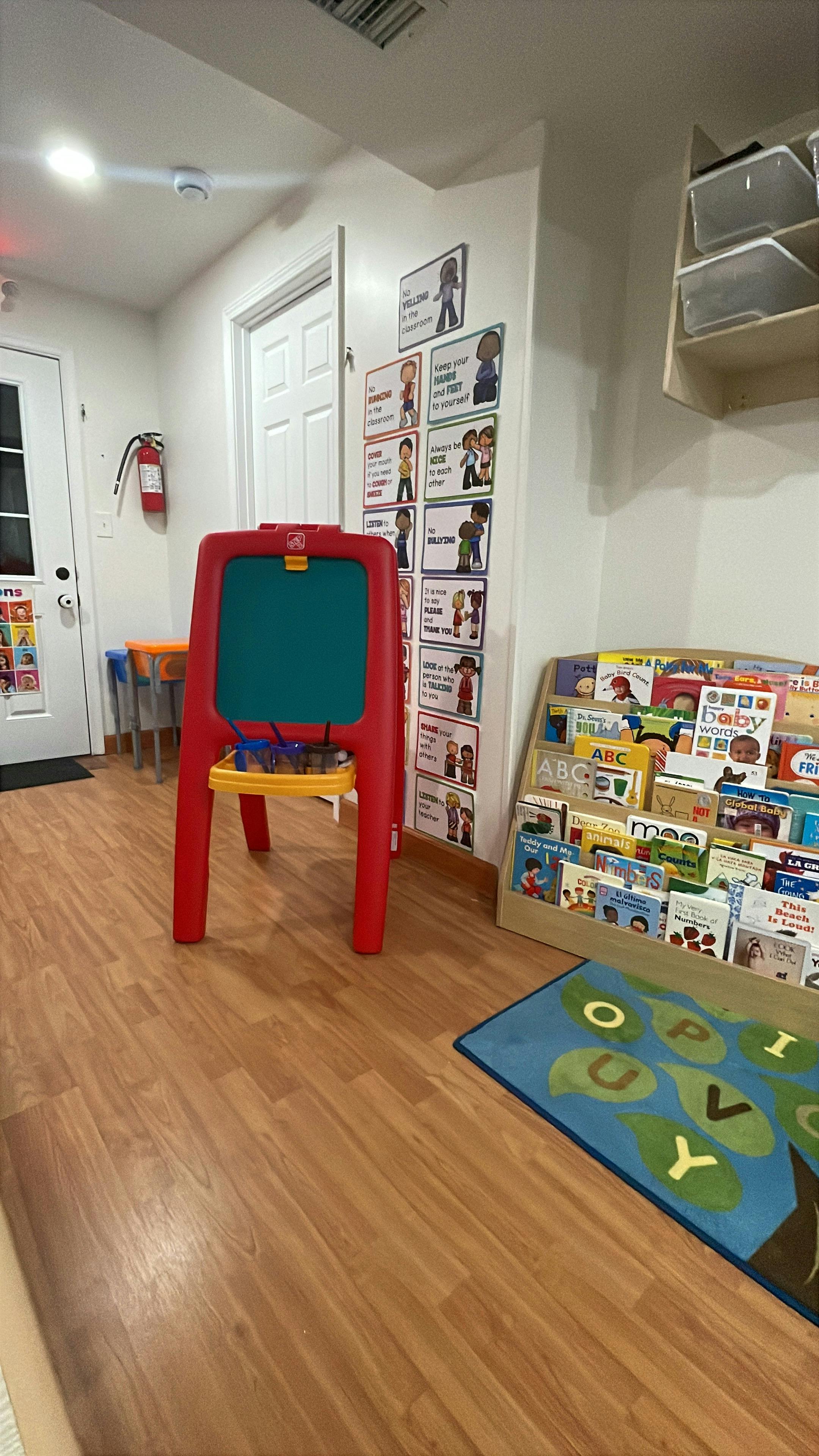 Red easel in a classroom with a book display and alphabet rug