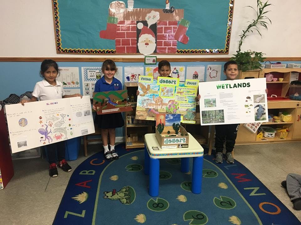Four children holding up school projects