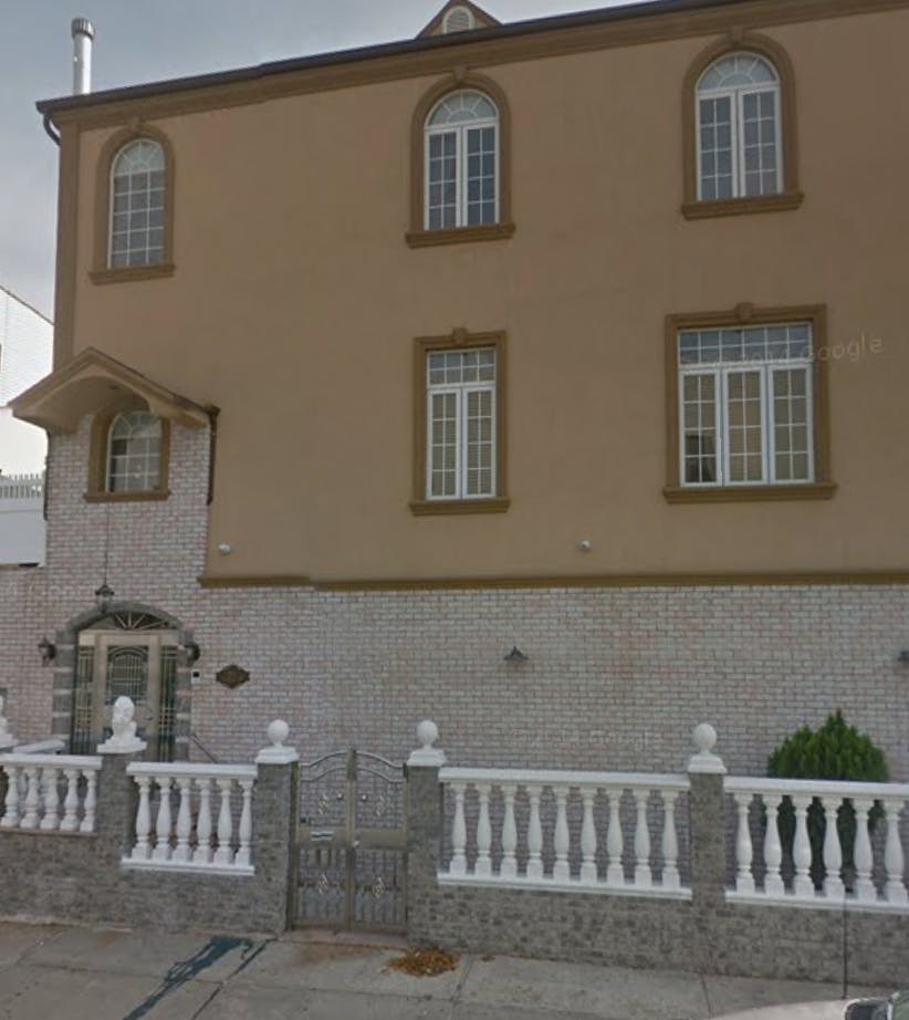 Three-story building with arched windows and a white balustrade fence