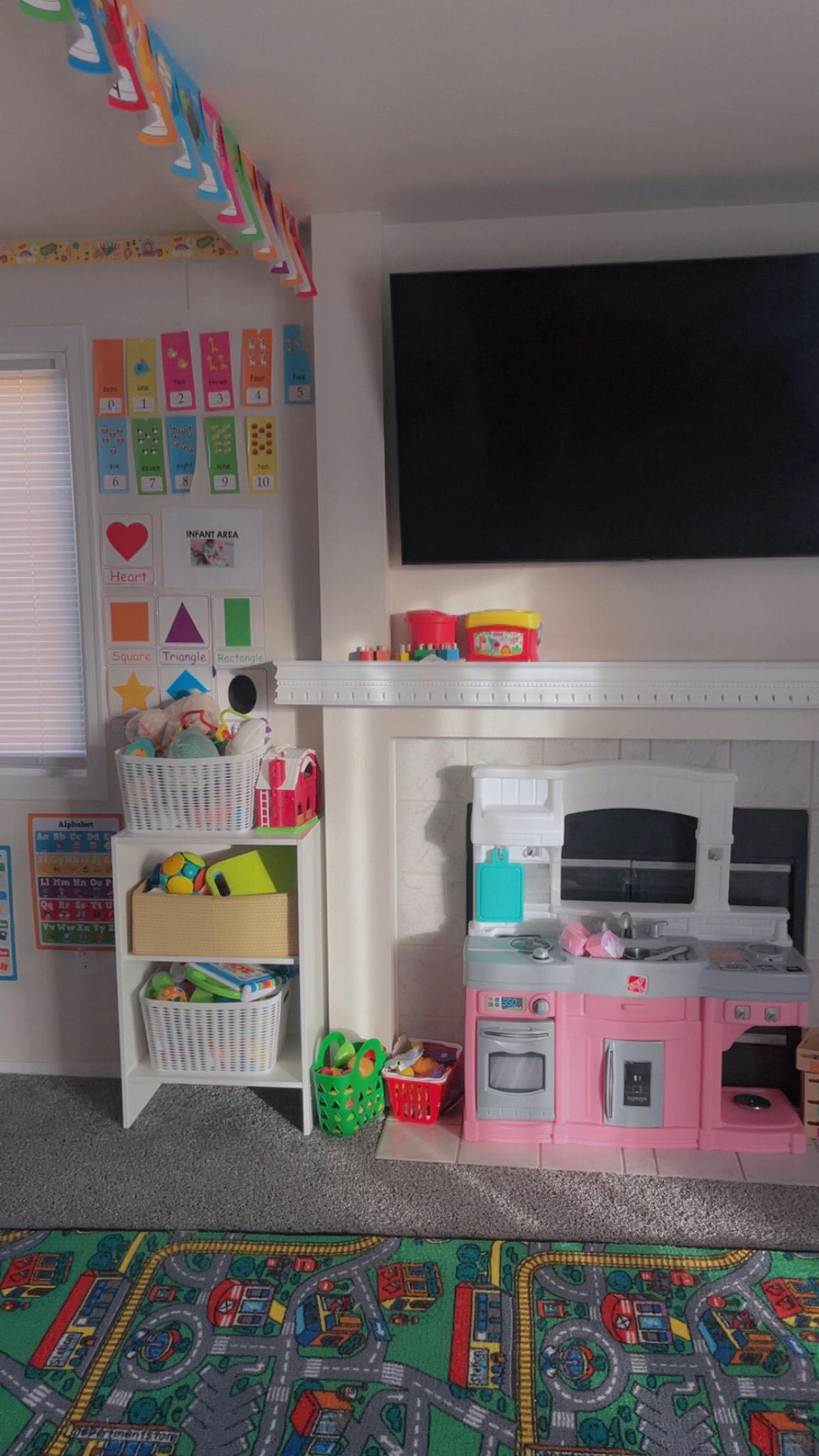 Playroom with toy kitchen, storage shelves, and colorful rug