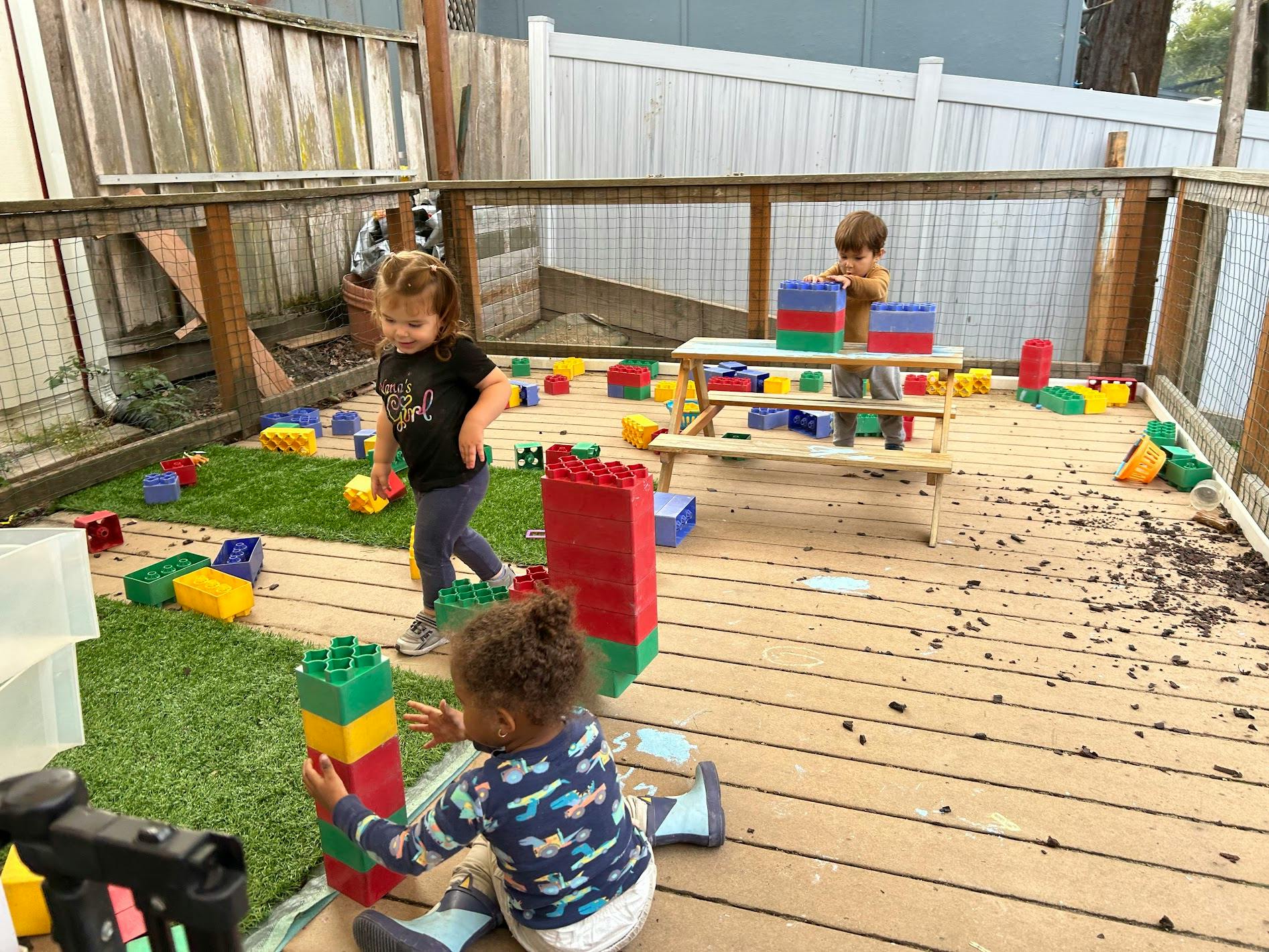 Children playing with large plastic building blocks on a deck