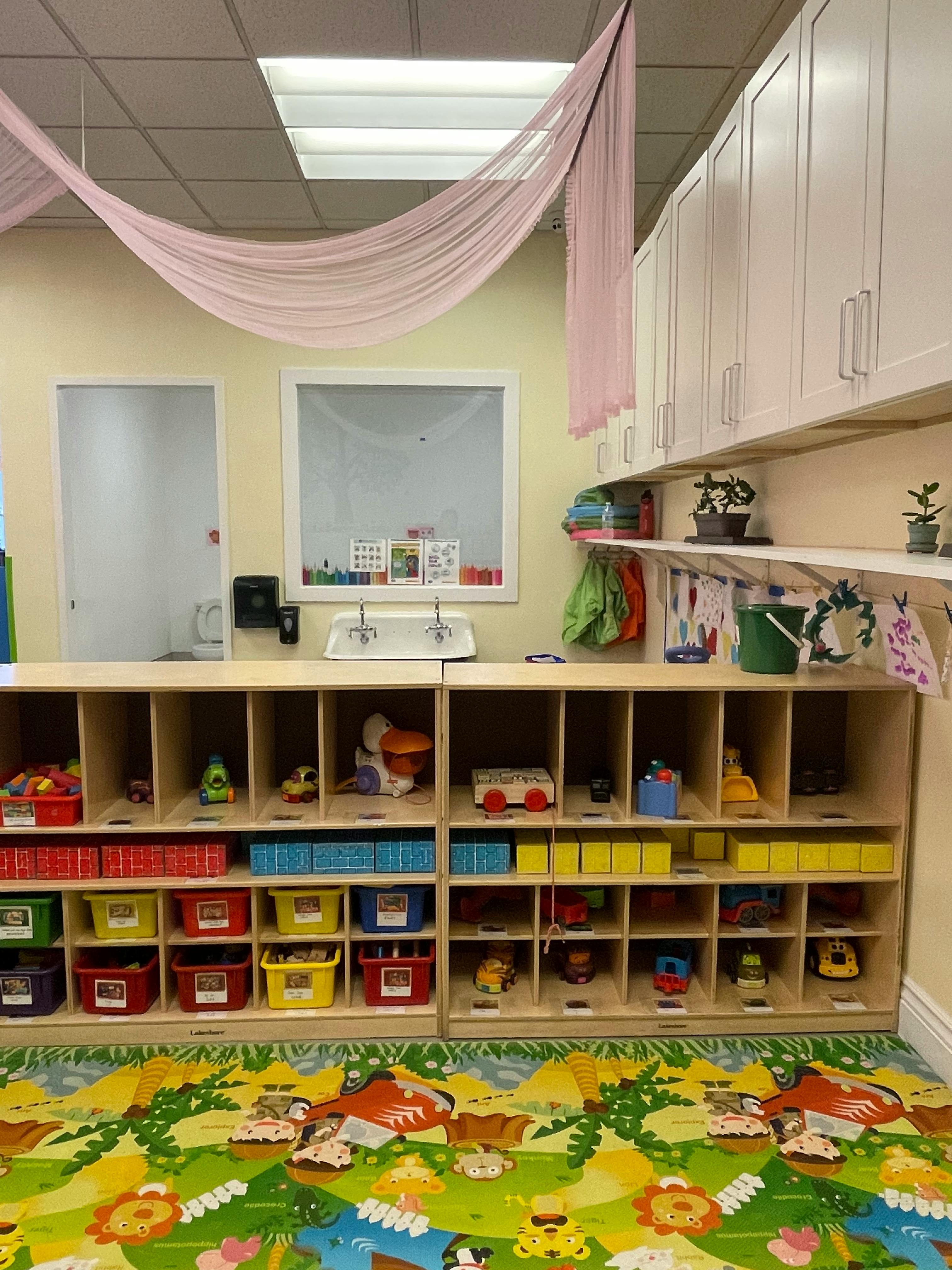 Classroom with cubbies full of toys and a colorful rug