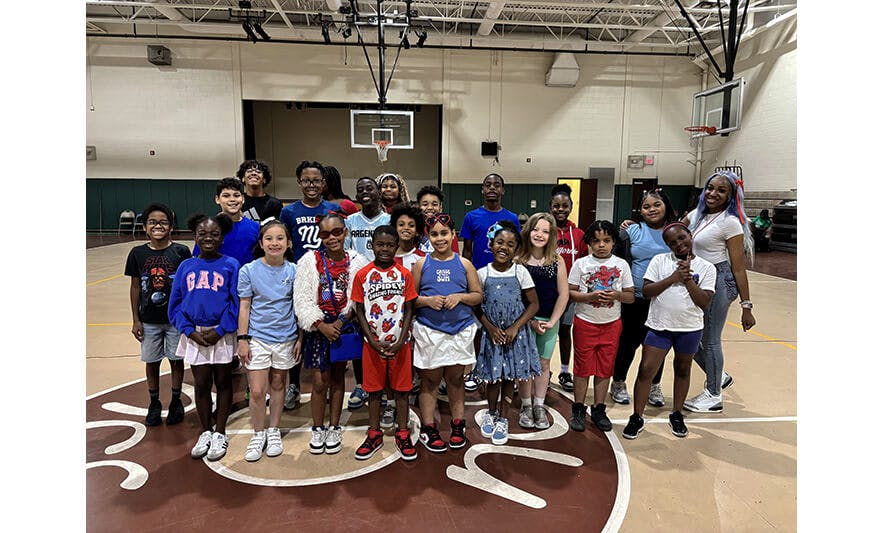 Group of children and adults standing on a basketball court