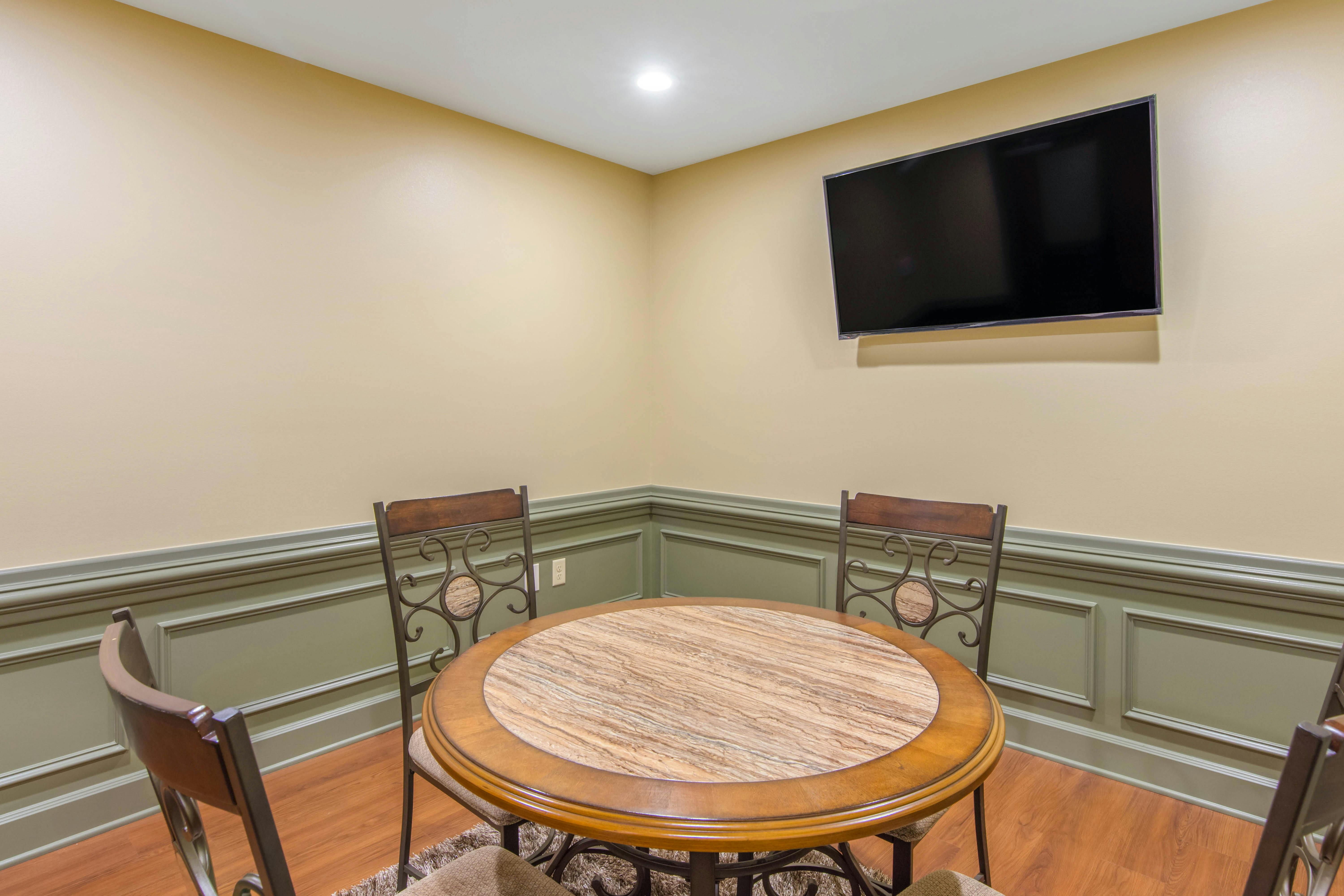 Small round table with four chairs in a room with a TV mounted on the wall