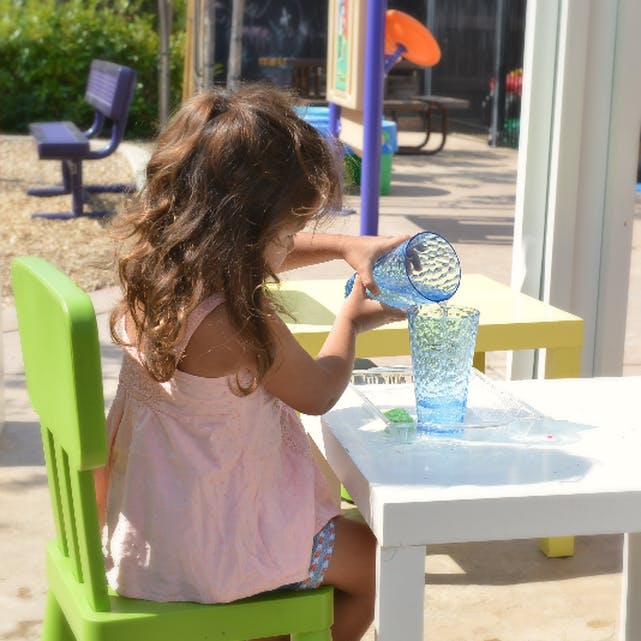 Child pouring water from one blue glass into another