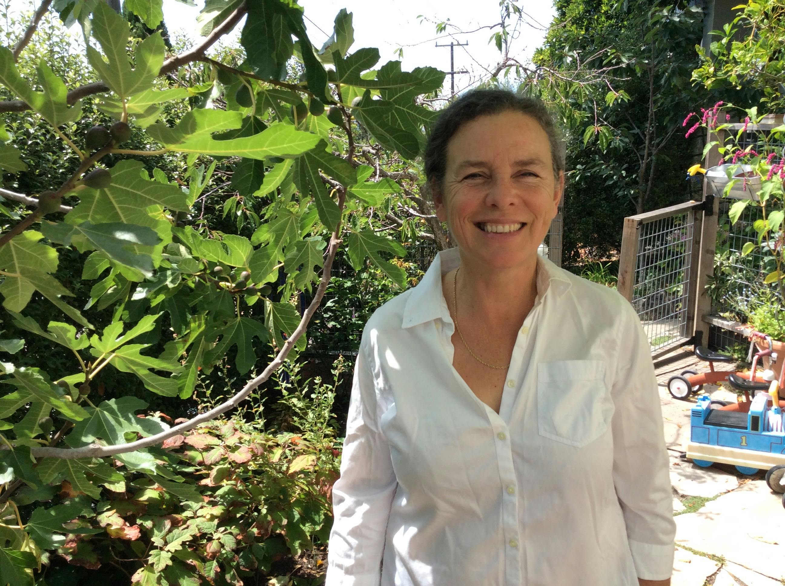 Person in a white button-down shirt standing in a garden