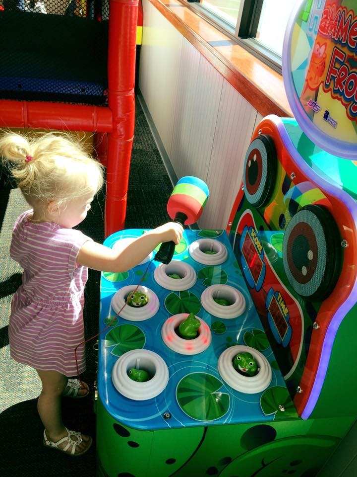 Child playing a whack-a-mole arcade game