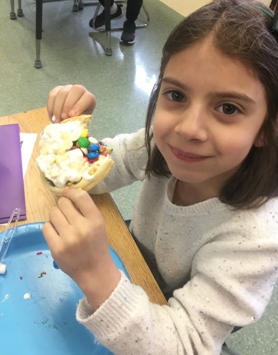 Child holding a dessert with whipped cream and colorful candies