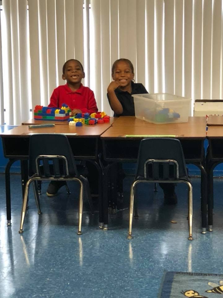 Two children sitting at a desk with colorful building blocks