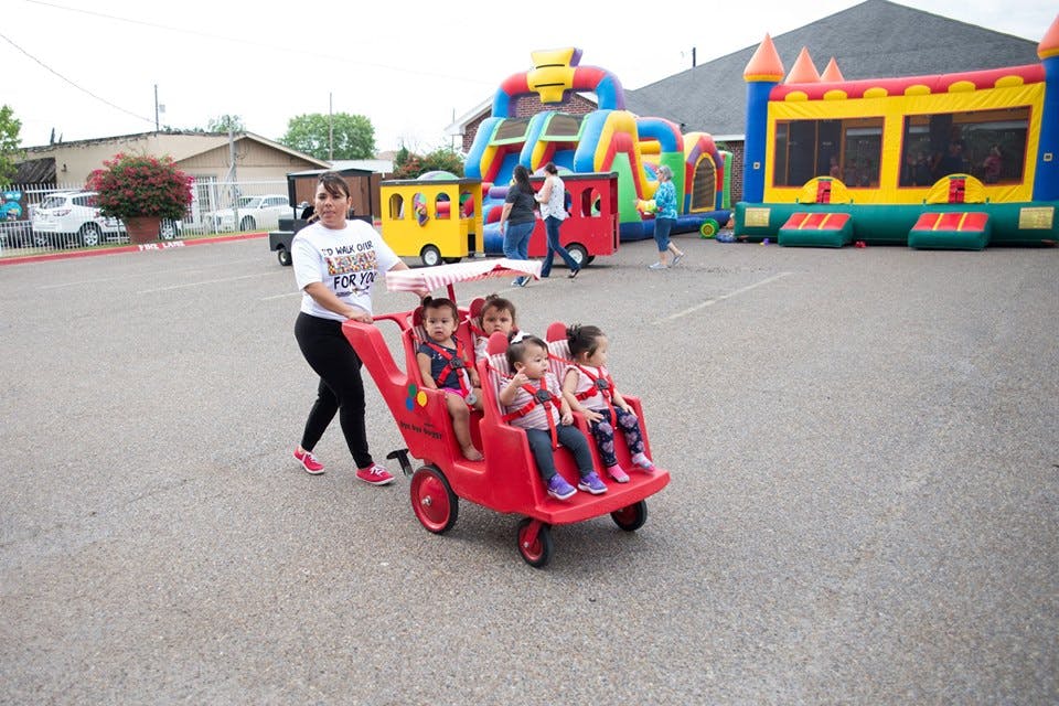 Person pushing multiple children in a red wagon