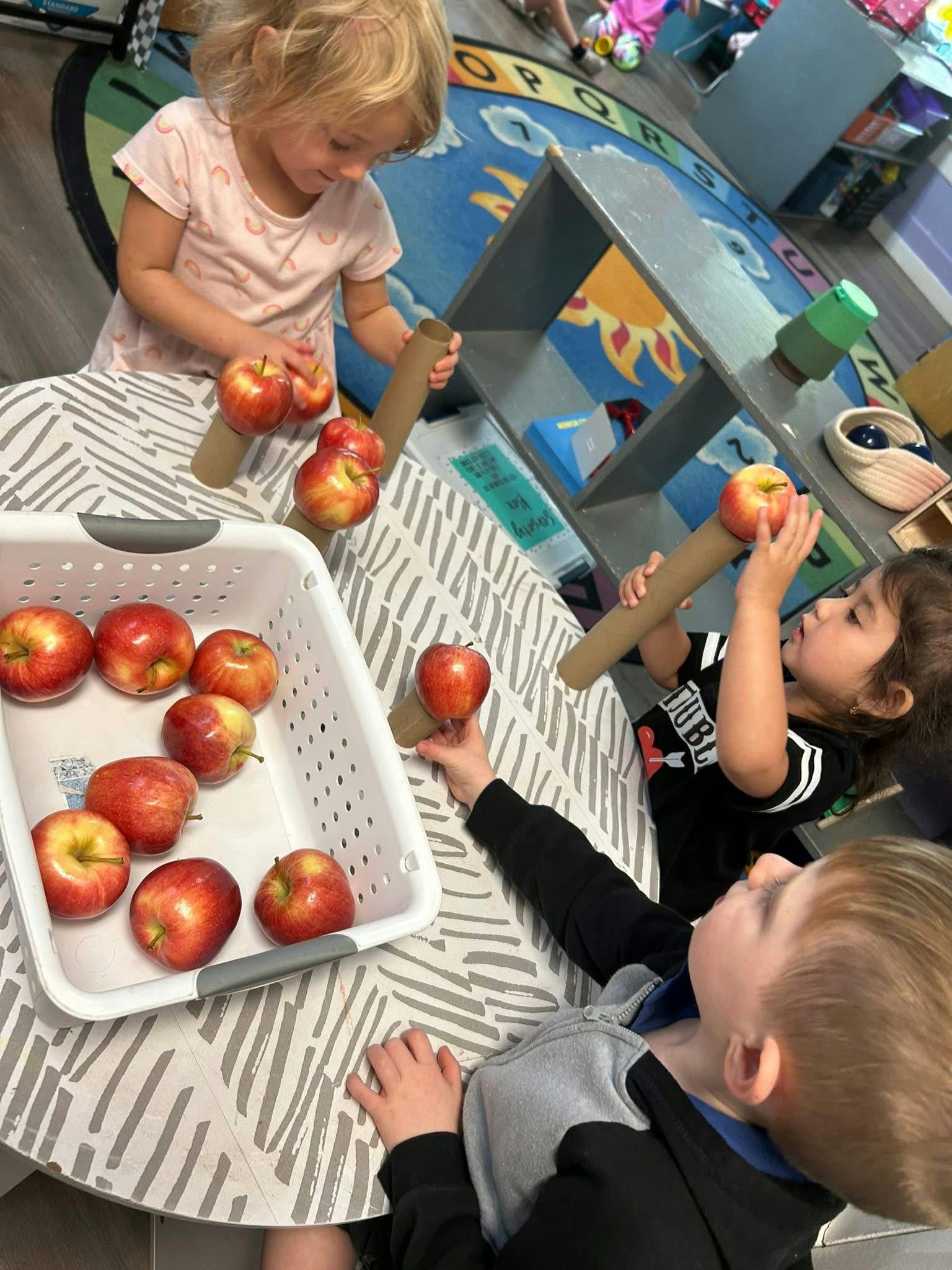 Children playing with apples and cardboard tubes