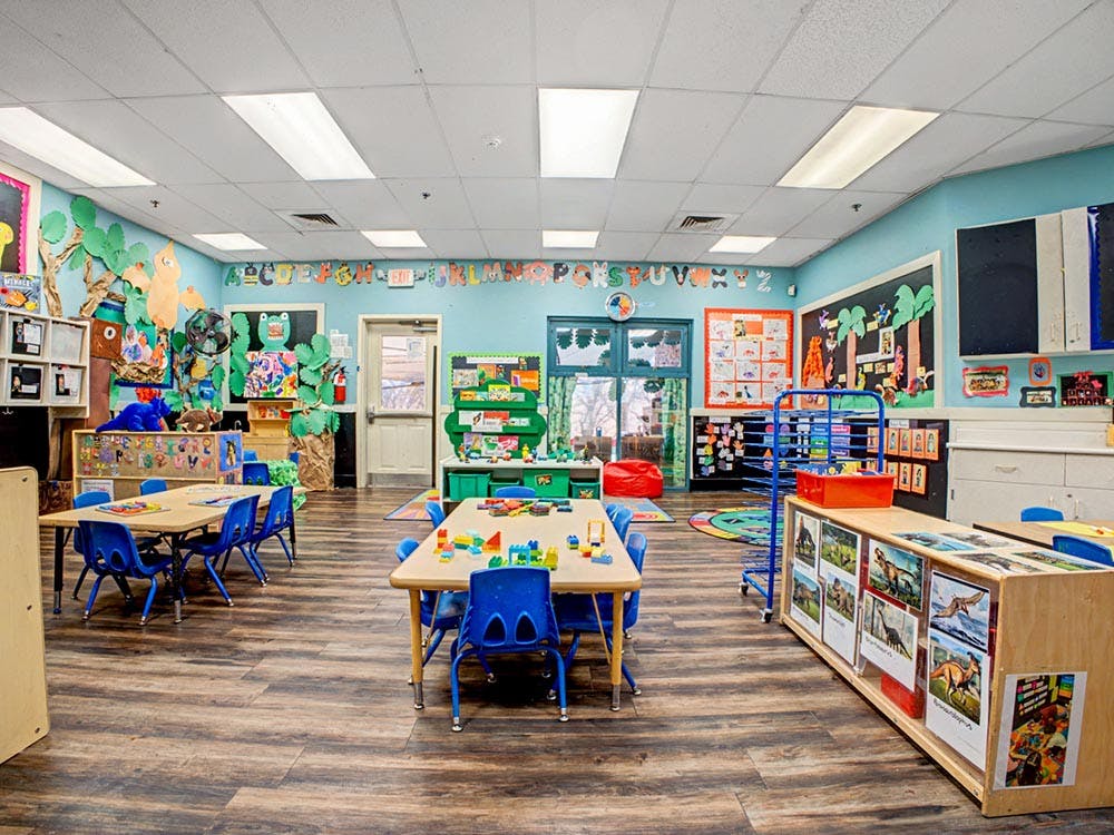 Classroom with child-sized tables and chairs, decorated walls, and learning materials