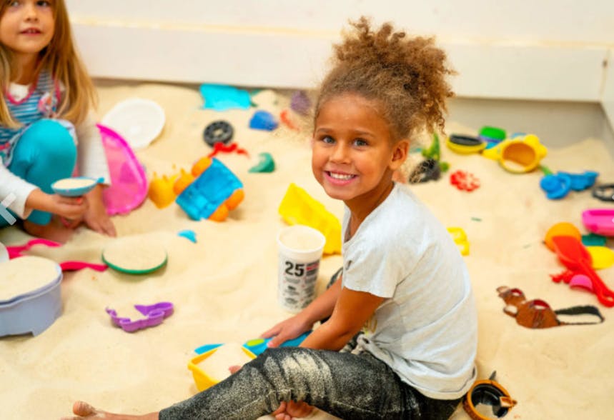 Child playing in sand with toys