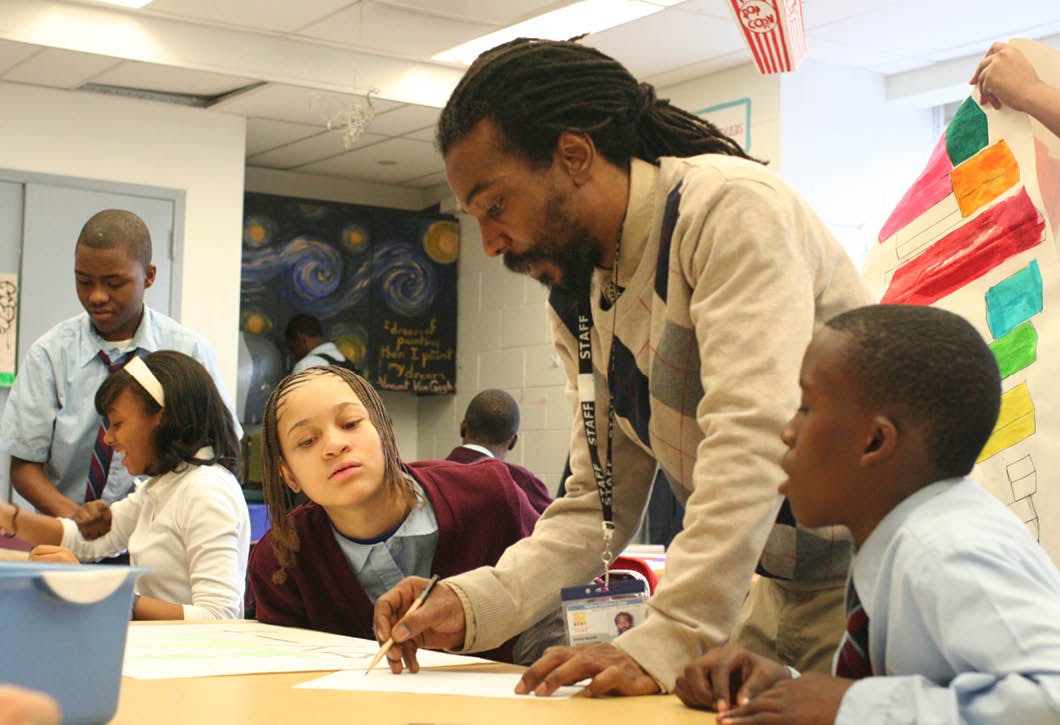 Adult person helping children with schoolwork in a classroom