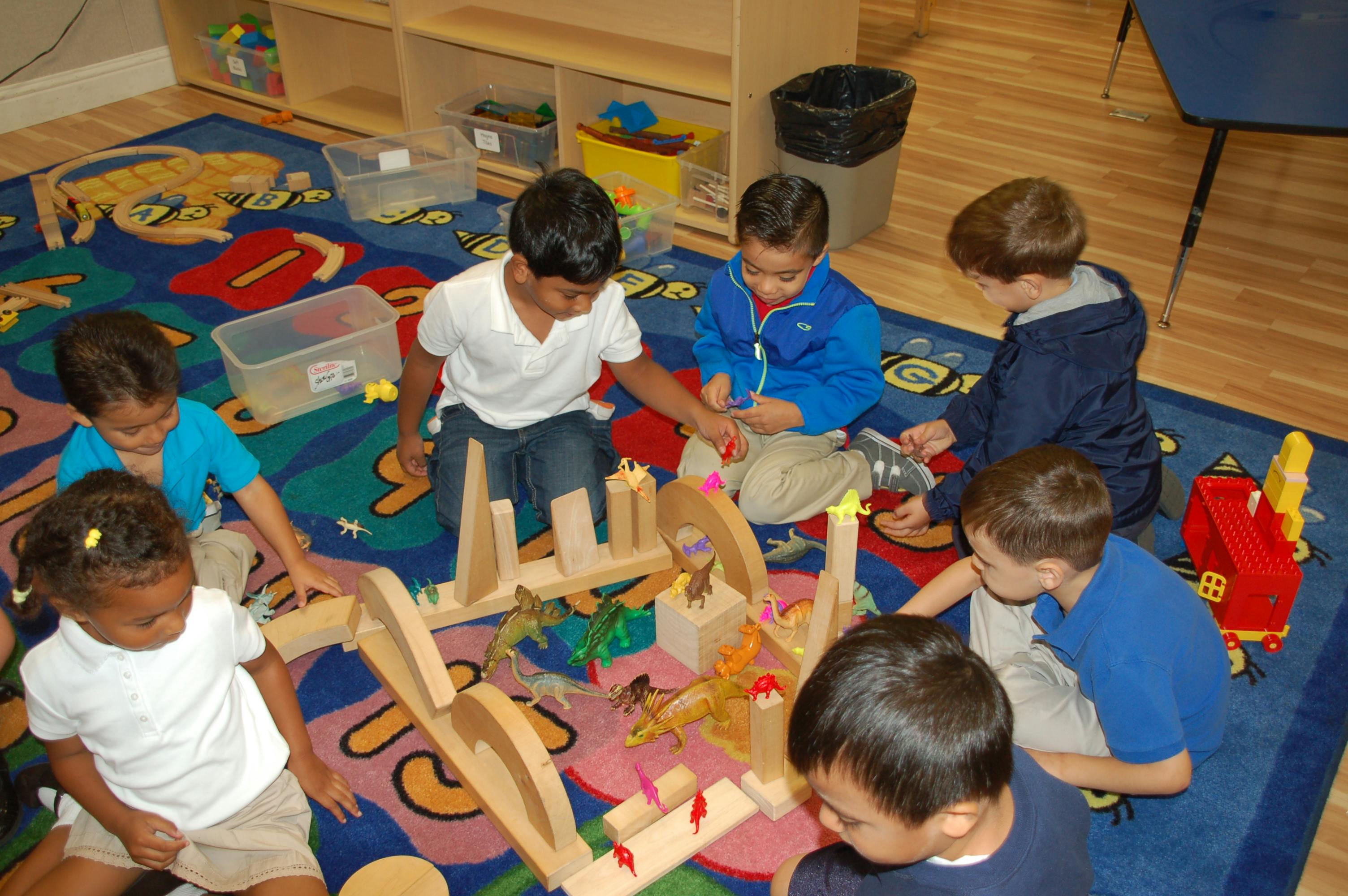 Children playing with wooden blocks on a colorful rug