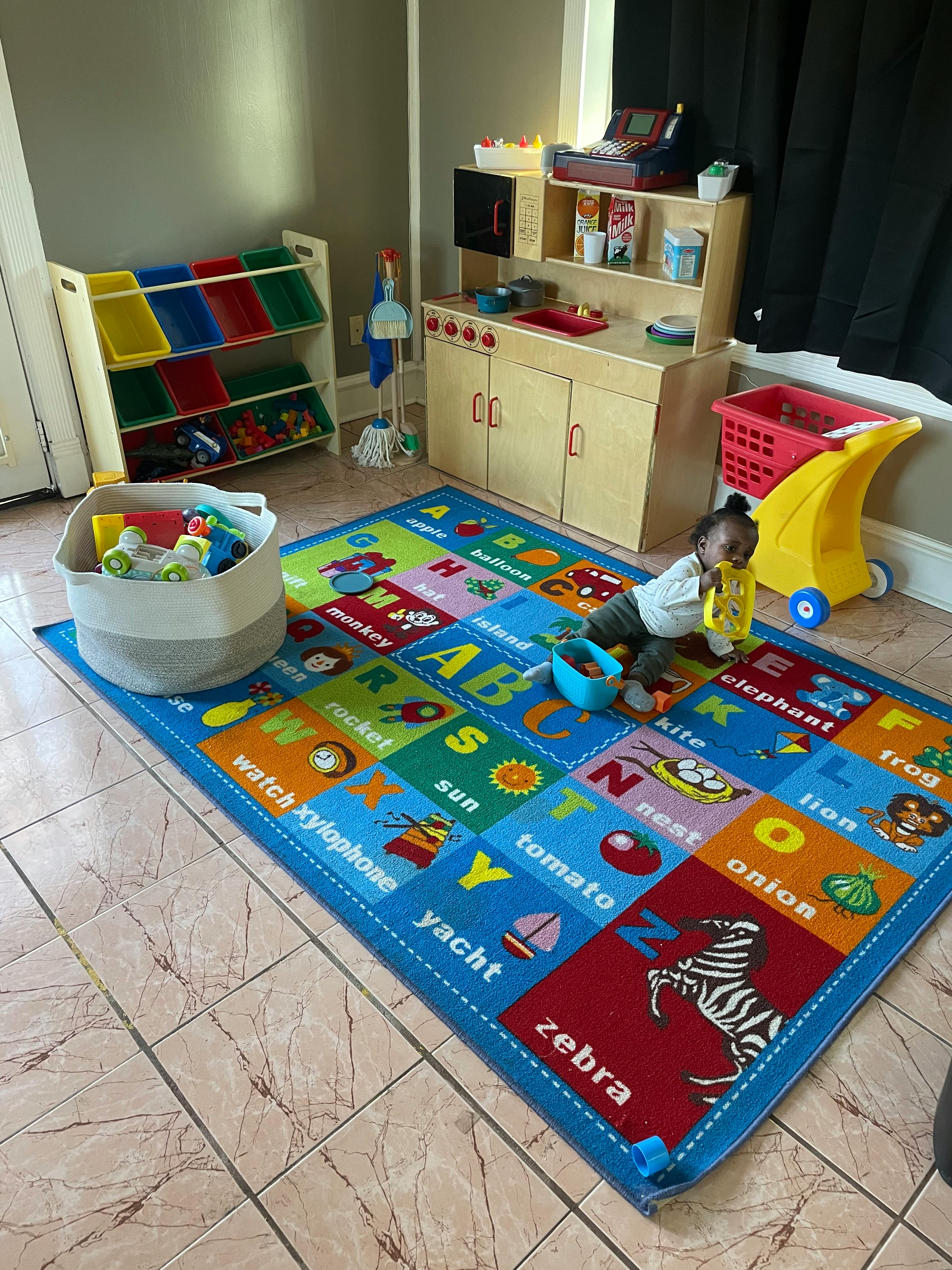Child playing on an alphabet rug in a playroom