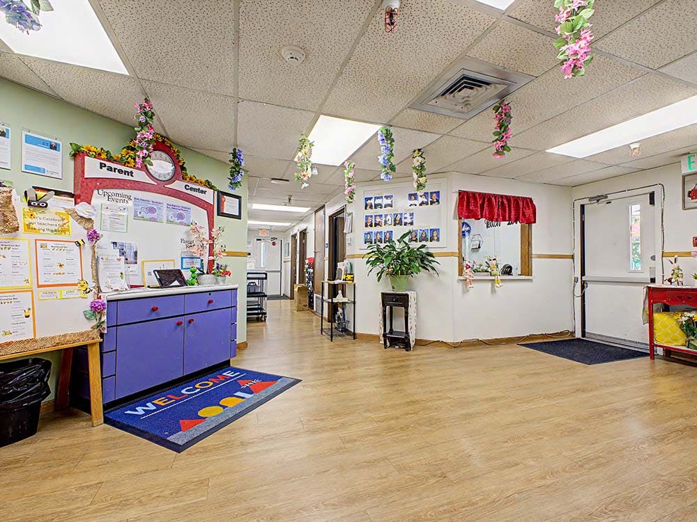 Lobby of a daycare or school with a counter, bulletin board, and welcome mat