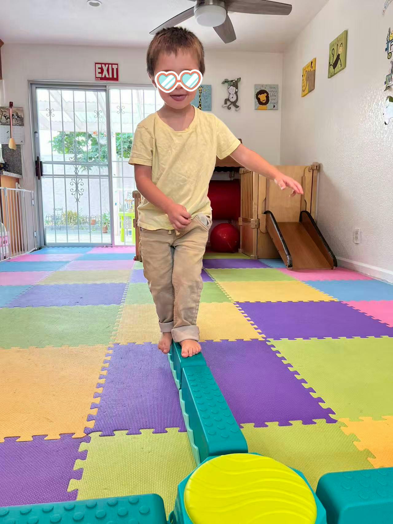 Child balancing on a green beam on a colorful foam floor