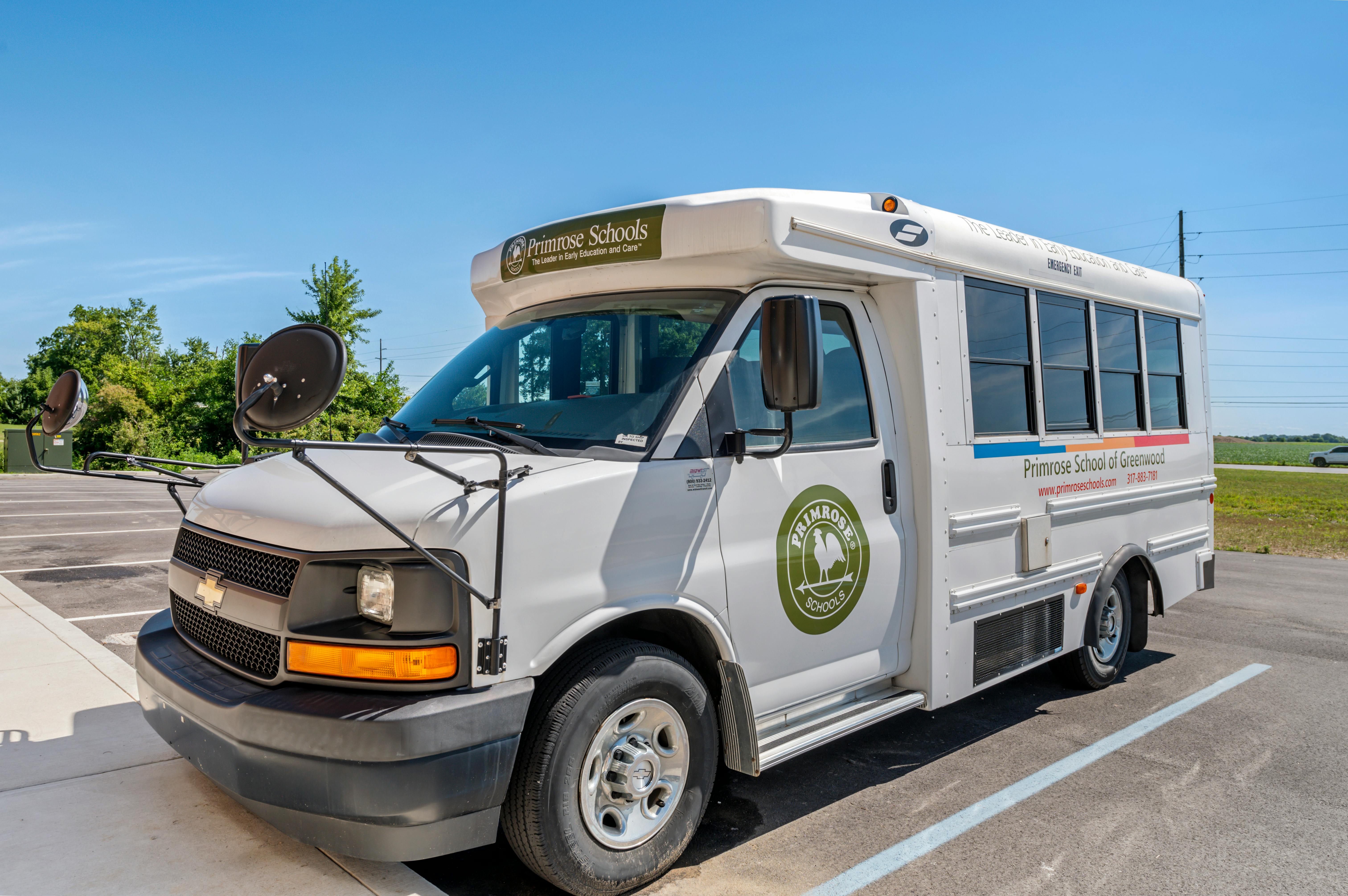 White school bus with "Primrose Schools" logo and text, text on the side