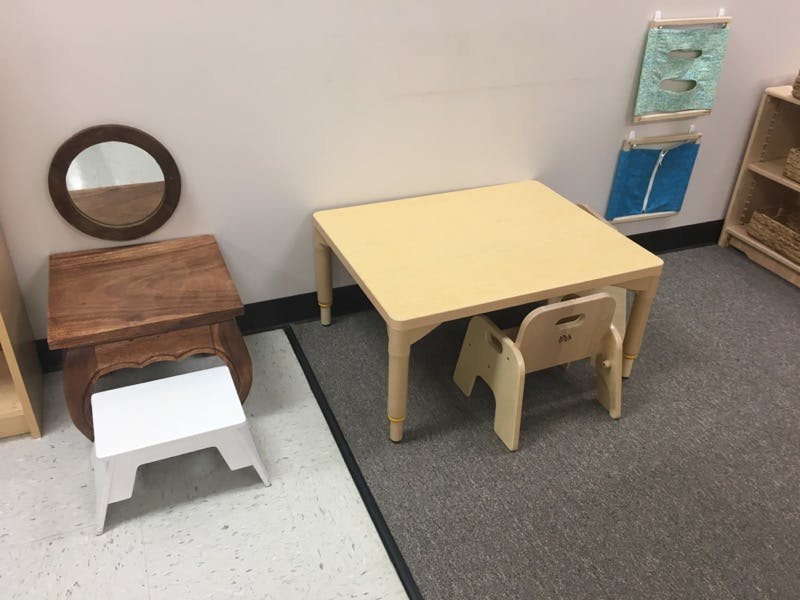 Small table and chair in a room with a mirror and stool