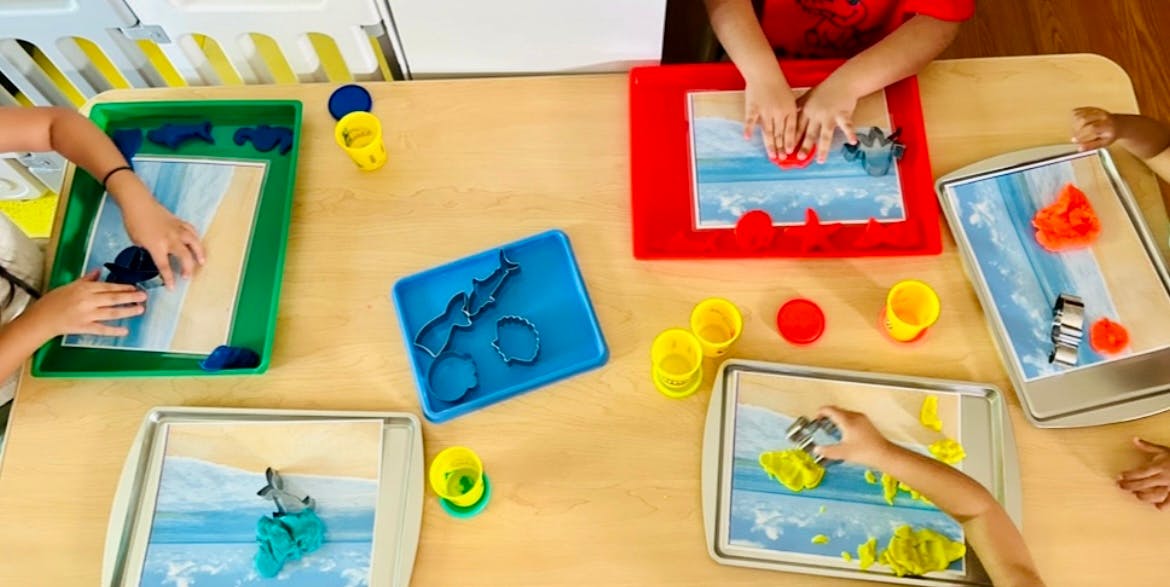 Children playing with sand and toys at a table