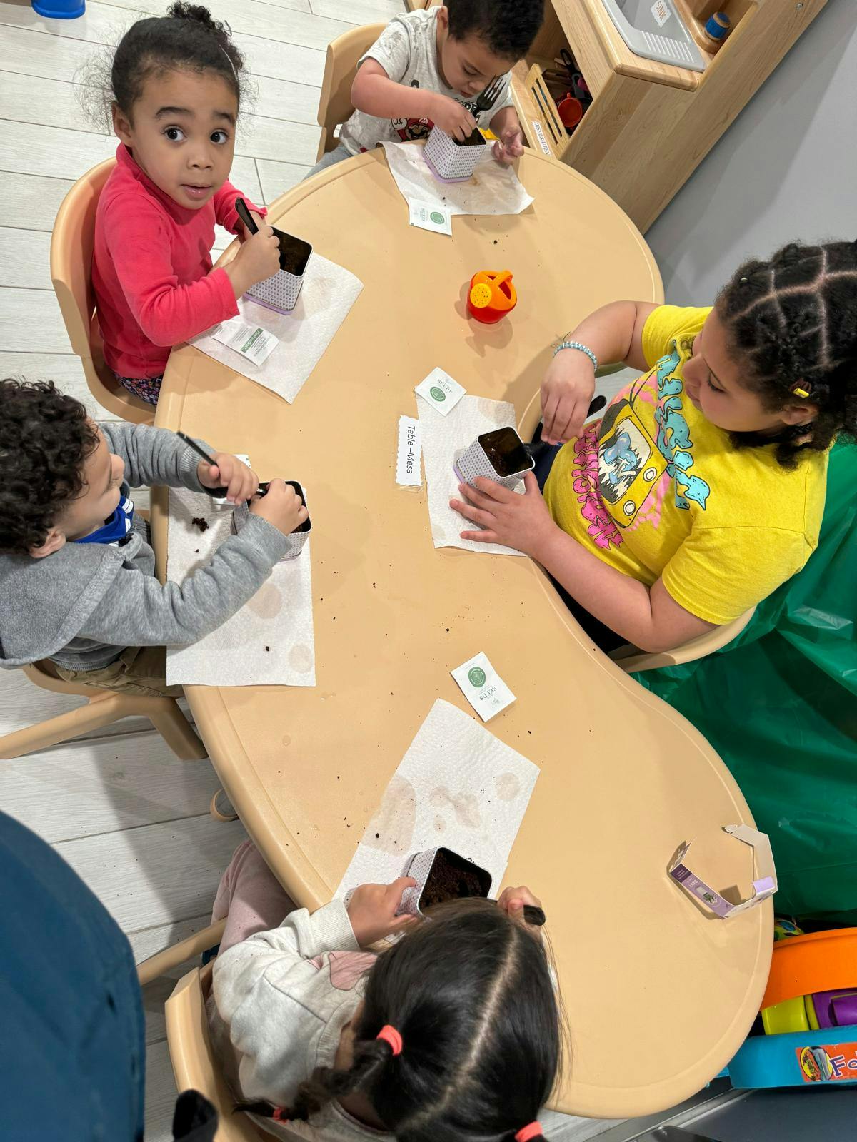 Children at a table planting seeds in small pots