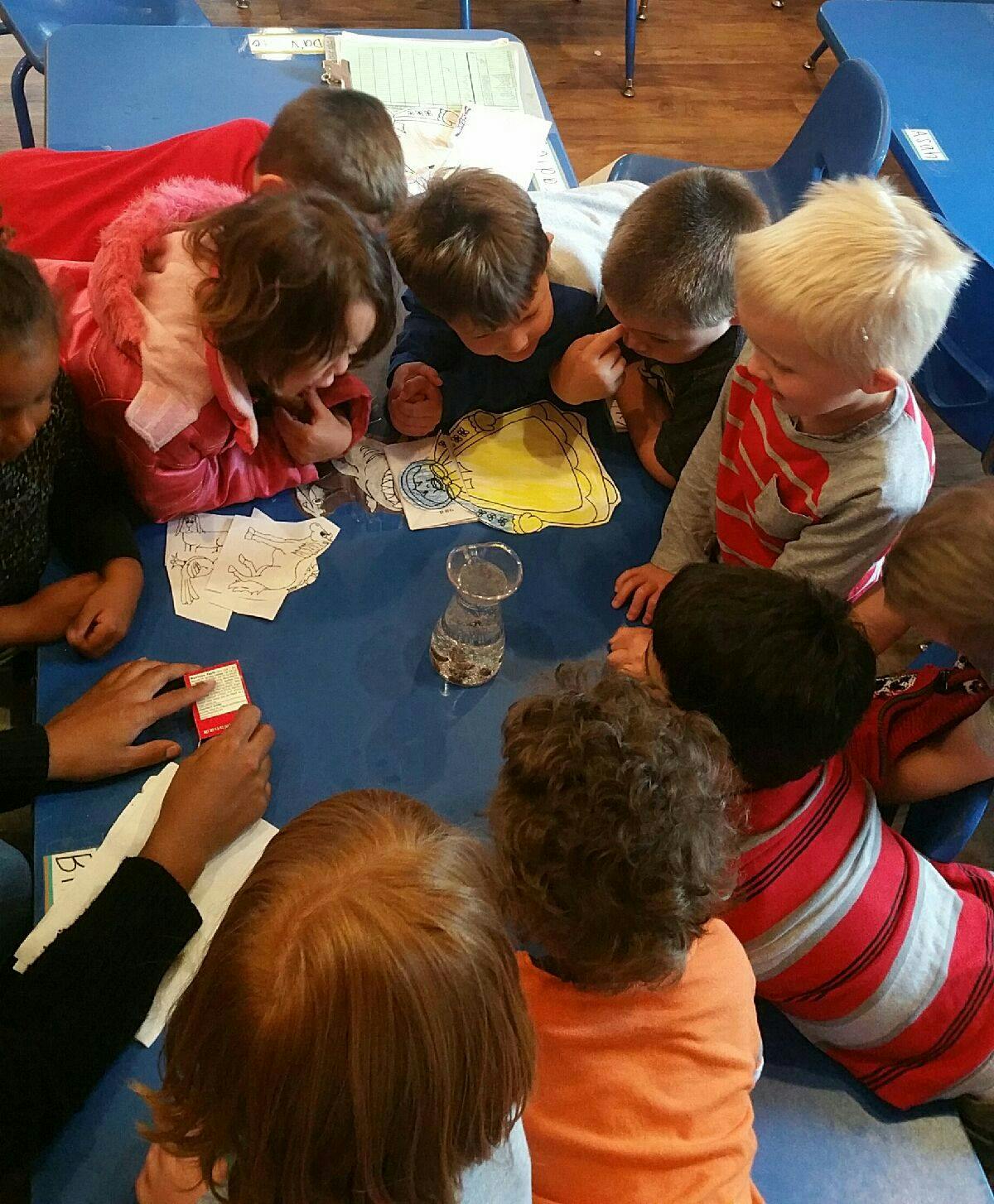 Children gathered around a table looking at items