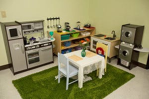 Play kitchen with toy appliances, table, and chairs