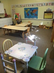 Classroom with small tables and chairs, world map on wall