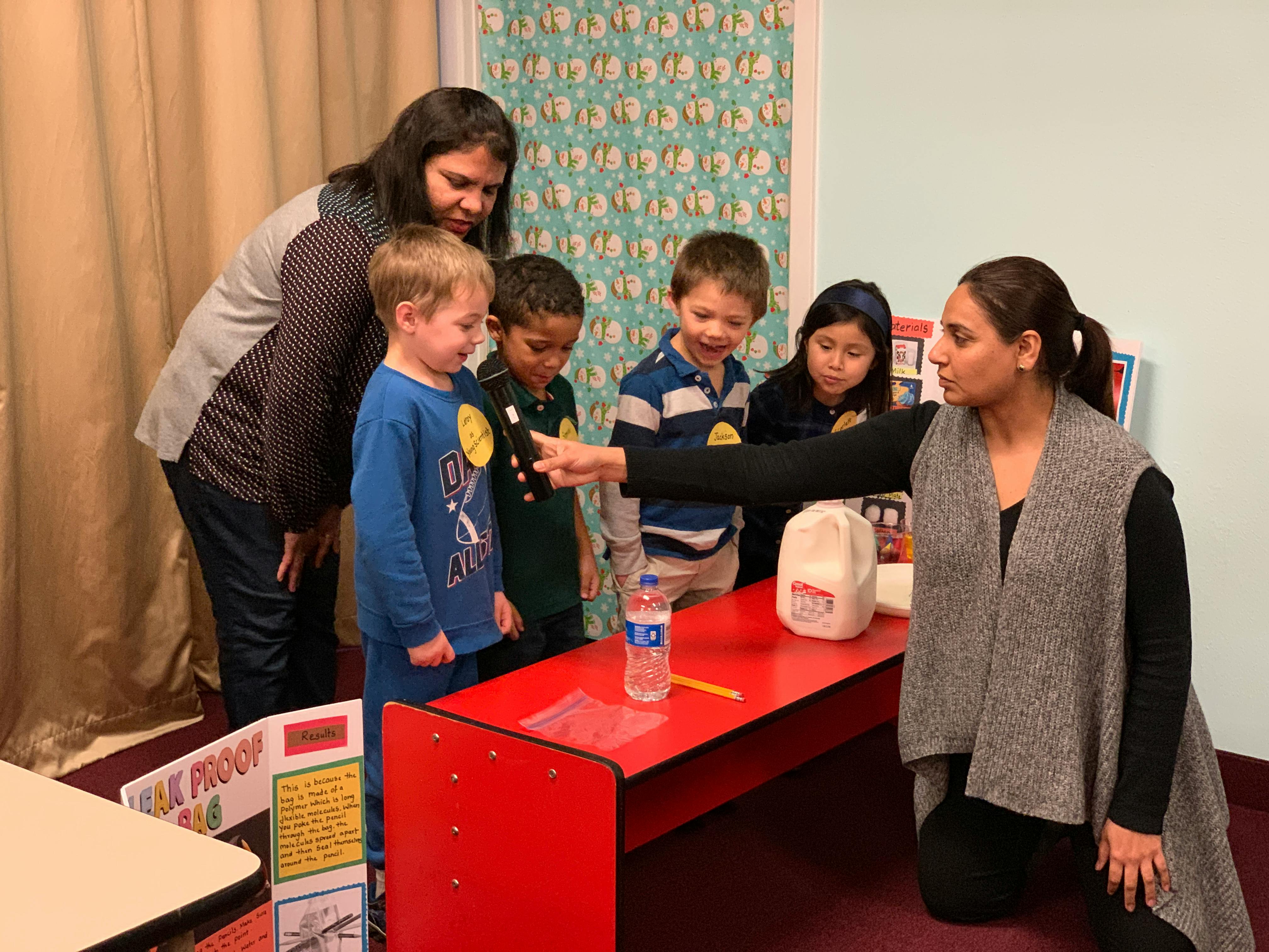 Adults and children gathered around a table with a bottle and milk jug