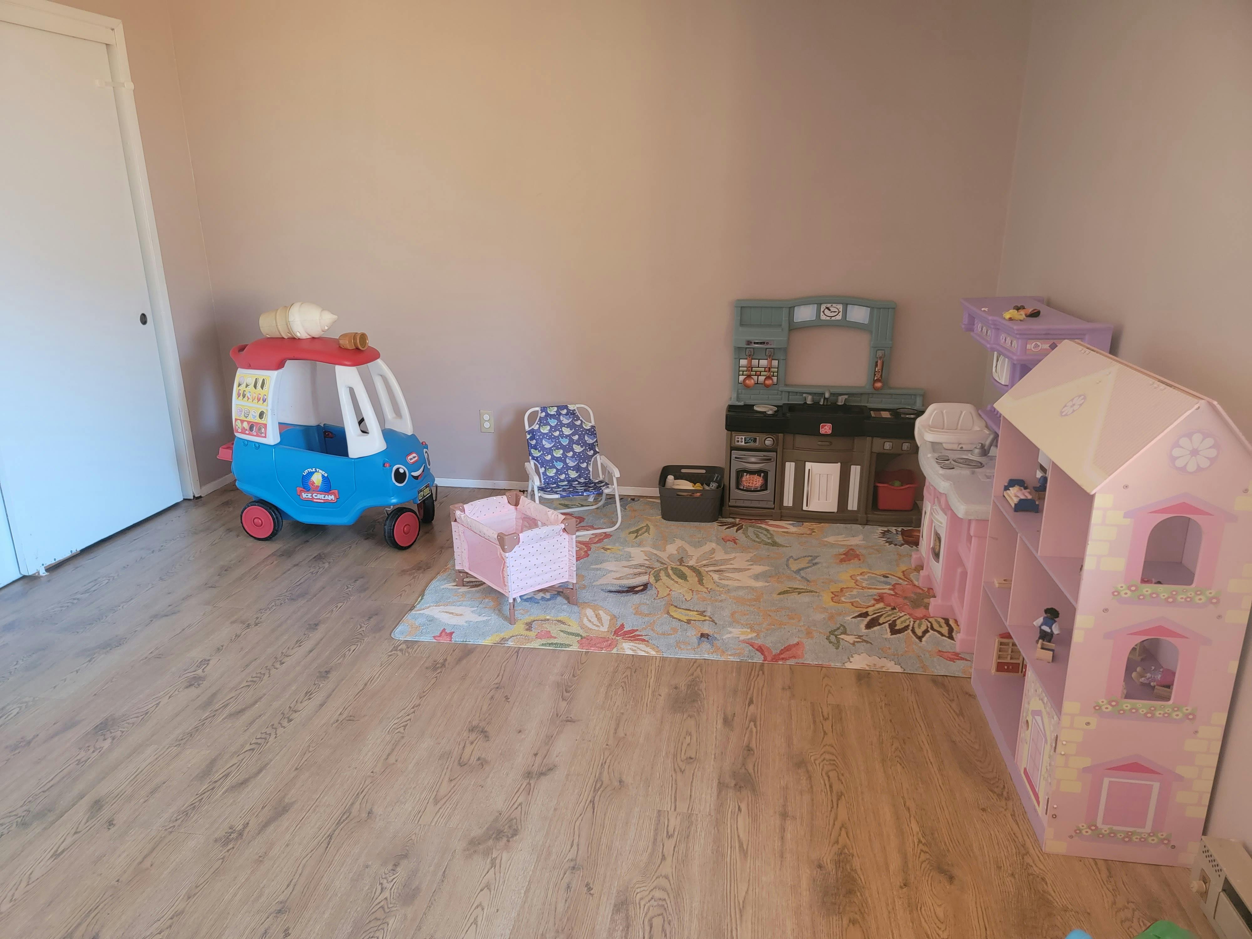 Children's play area with toy car, dollhouse, and play kitchen