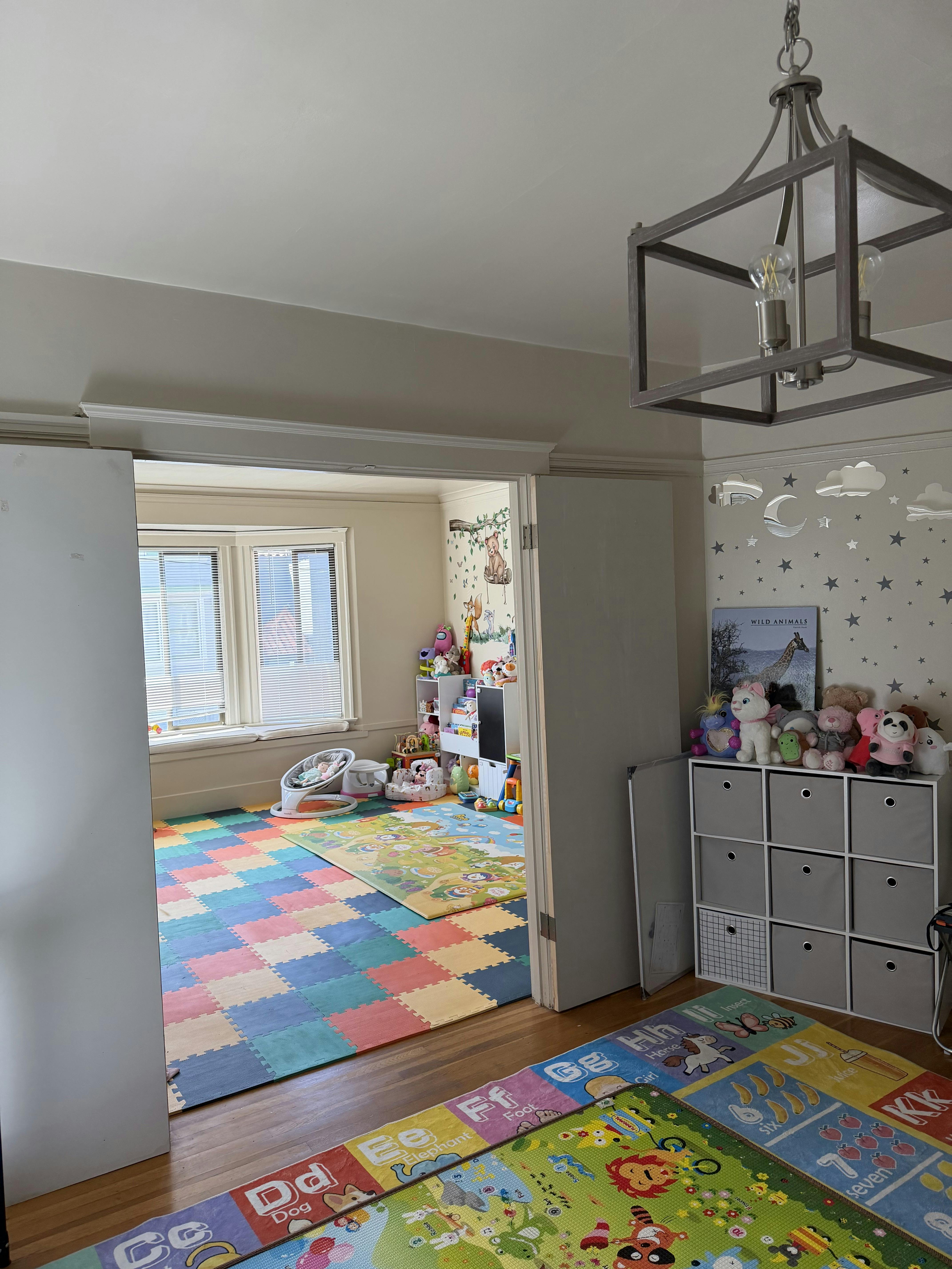 A playroom with colorful floor mats, toys, and a stuffed animal collection